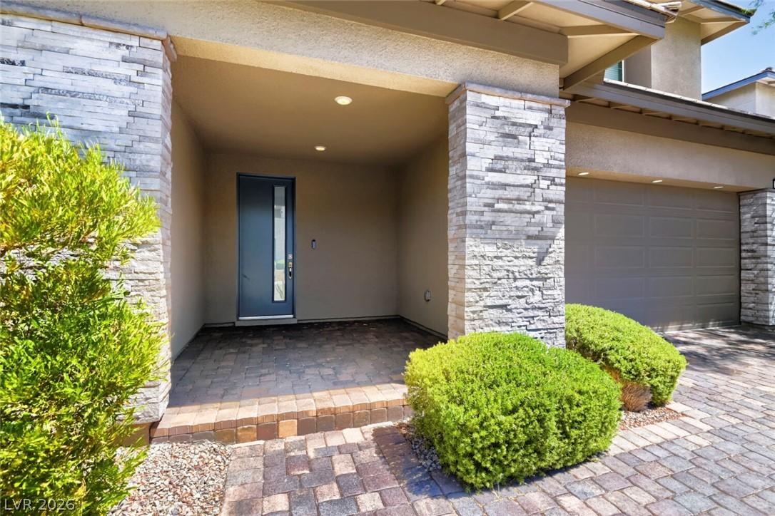 Image 2: A welcoming entry features stone veneer pillars, a