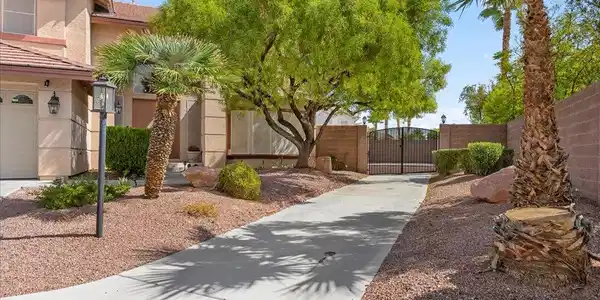 Image 4: A concrete driveway leads past desert landscaping