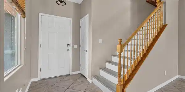Image 4: Tile flooring leads past a classic wooden staircas