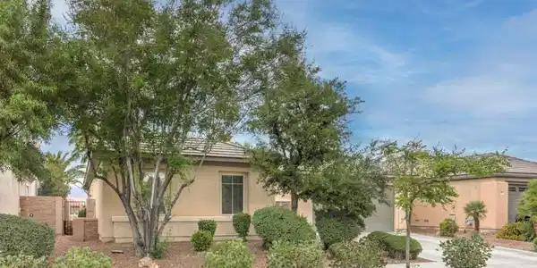 Image 2: Lush landscaping and mature trees frame the stucco