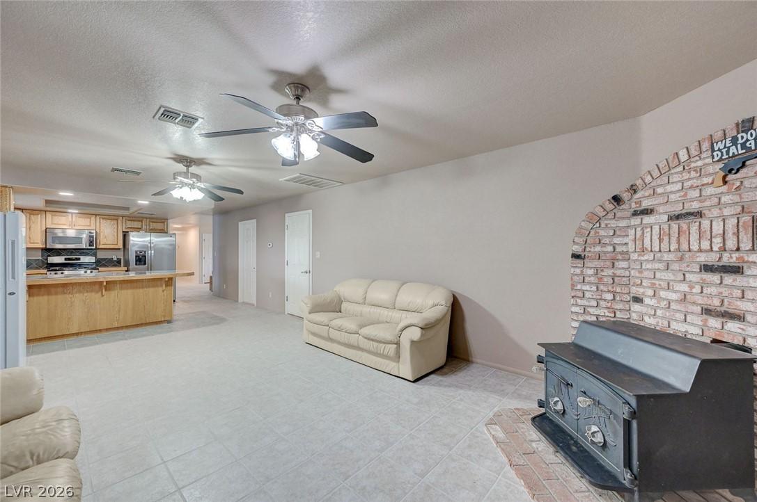 Image 3: Living room with a wood stove, a textured ceiling,