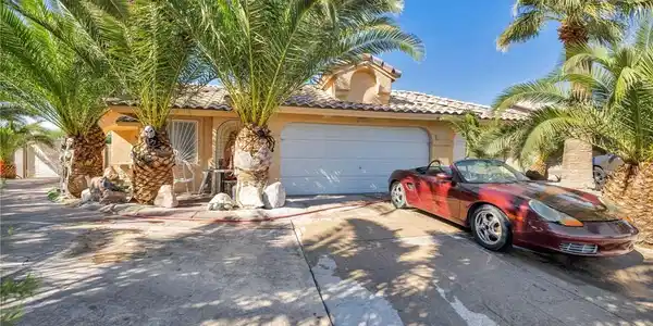 Image 3: Palm trees frame the classic stucco exterior and t