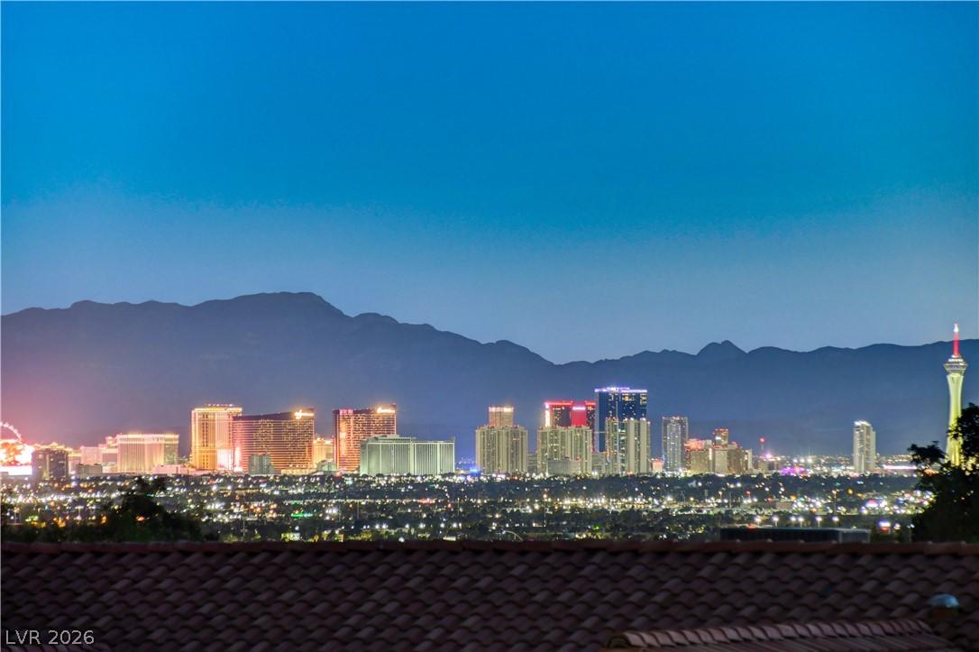 Image 1: Dramatic cityscape at dusk with distant mountains