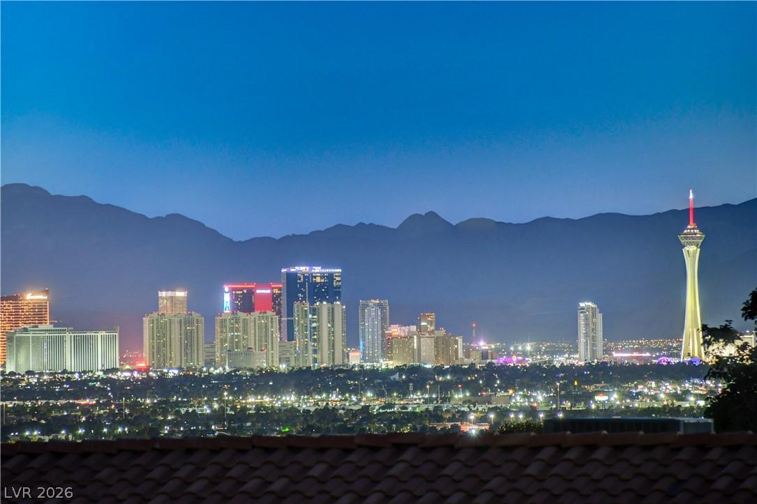 Image 3: City lights glow against a mountain backdrop under