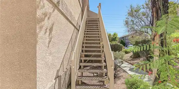 Image 2: An outdoor staircase ascends the side of a stucco