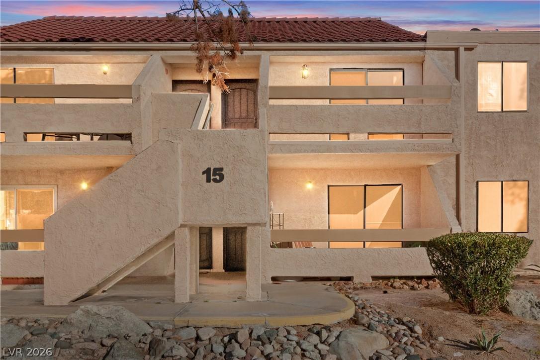 Image 2: Front of house at dusk with stucco siding and a ti