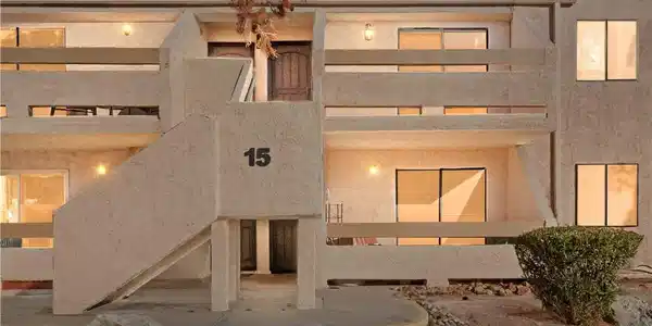 Image 2: Front of house at dusk with stucco siding and a ti