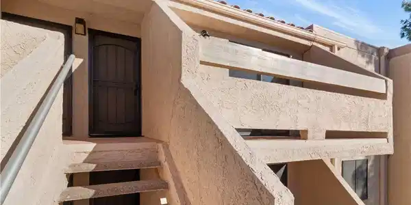 Image 3: View of exterior entry featuring stucco siding and