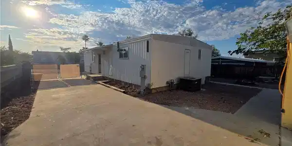 Image 4: A fenced, paved driveway leads to a modest, functi