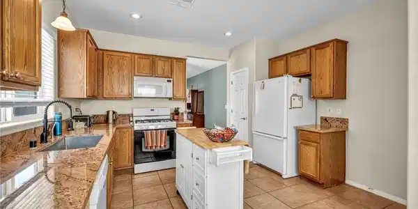 Image 4: Ample wooden cabinetry and polished stone countert