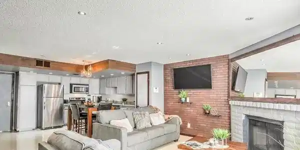 Image 2: A classic brick fireplace anchors the open-concept
