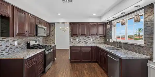 Image 2: Rich dark wood cabinetry and granite countertops f