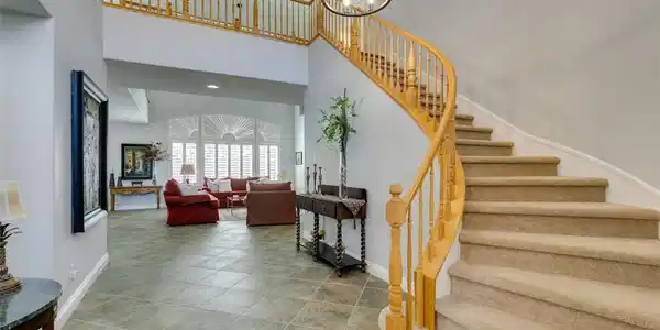 Image 4: An elegant curved staircase ascends from the tiled
