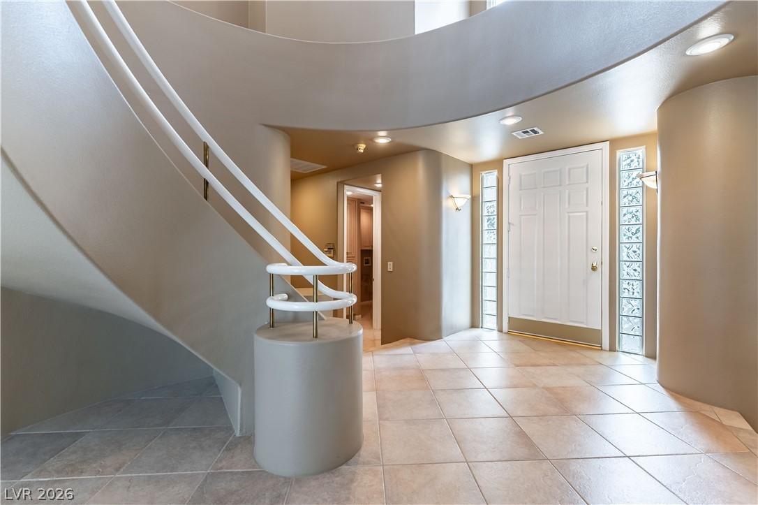 Image 3: A grand entry presents a graceful curved staircase