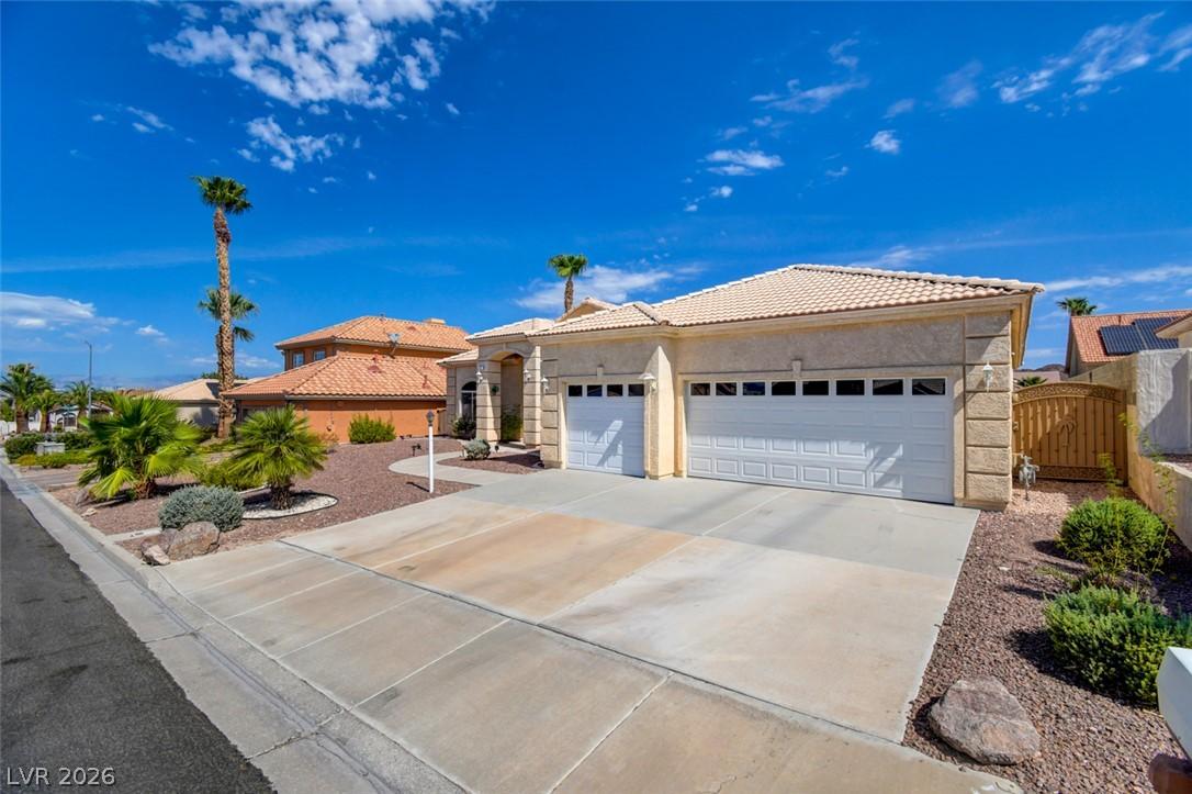 Image 2: A cream-colored stucco home with a tile roof and a