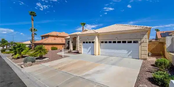 Image 2: A cream-colored stucco home with a tile roof and a