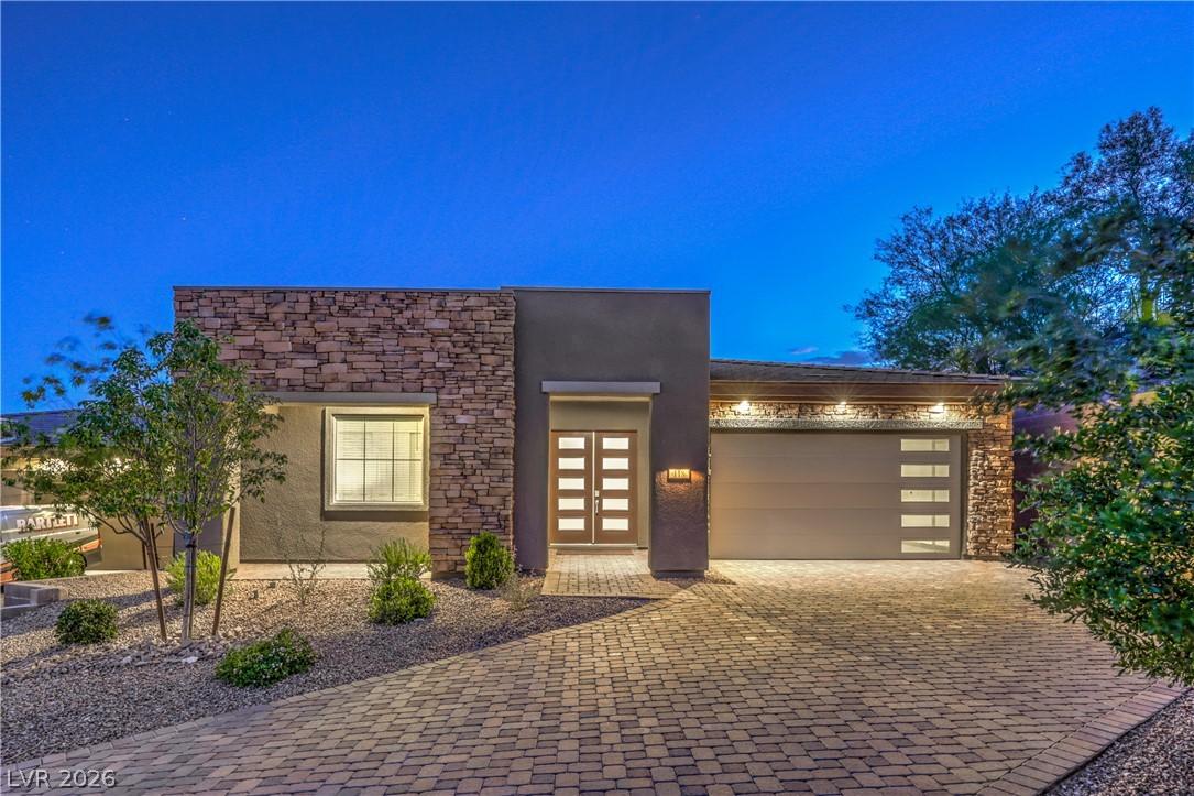 Image 1: A modern facade with stone accents and a paver dri