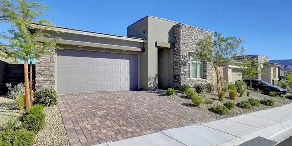 Image 2: A well-maintained front yard offers lush landscapi