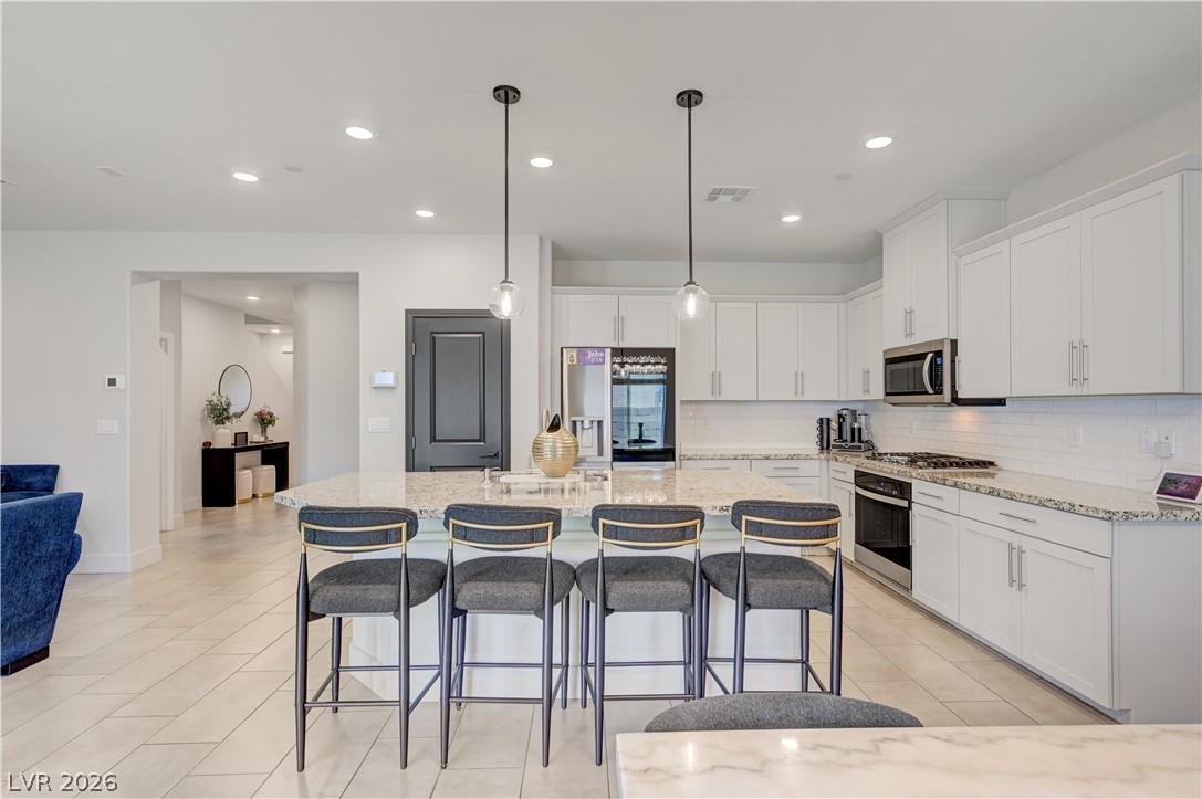 Image 4: A well-lit kitchen with white shaker cabinets, sta