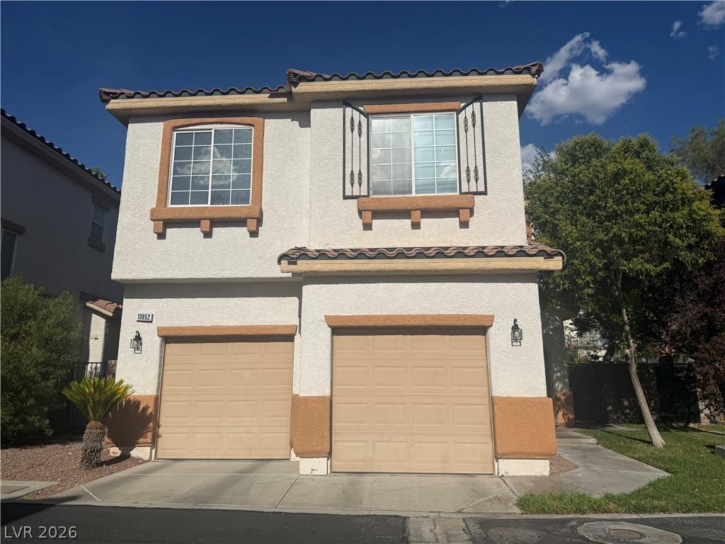Image 1: A charming two-story stucco home offers twin garag