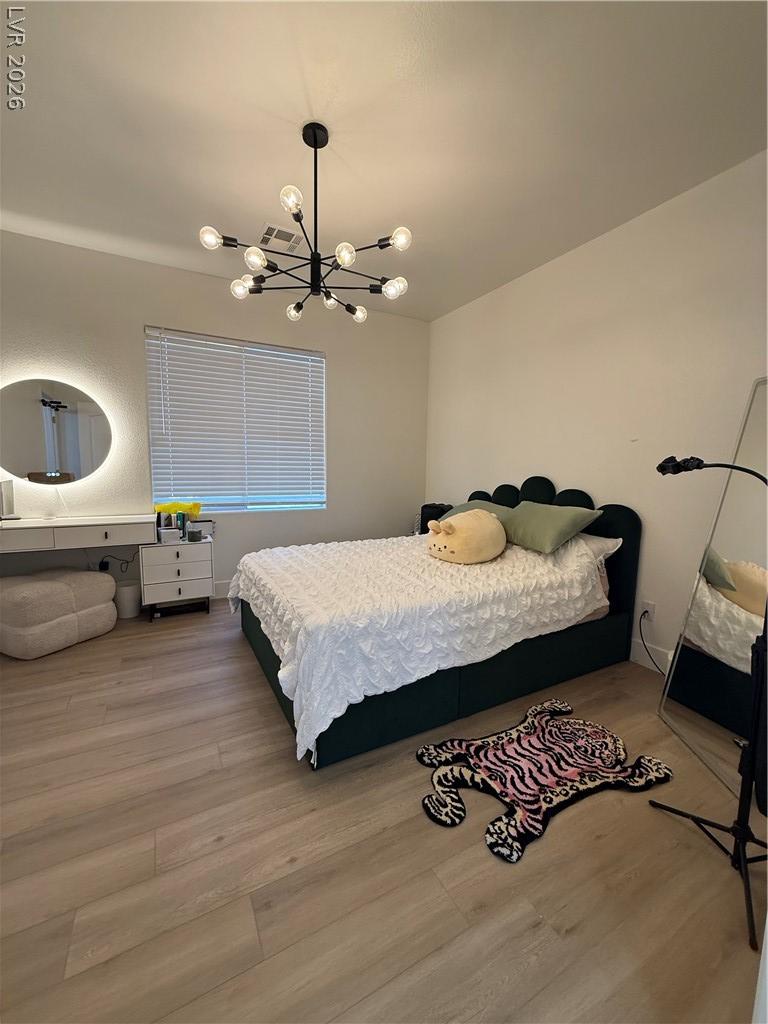 Image 4: This spacious bedroom features natural wood floori