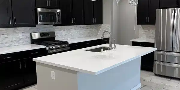 Image 4: A contemporary kitchen features dark cabinetry, st