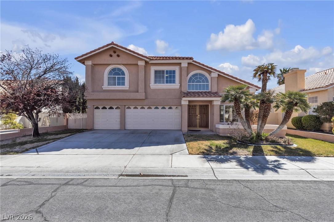 Image 1: A classic two-story stucco home features a dual ga