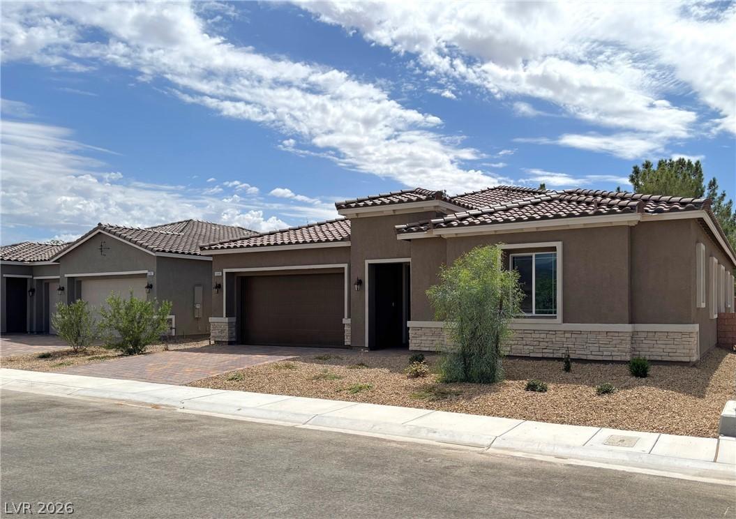 Image 2: View of front of home with stucco siding, stone si