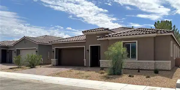 Image 2: View of front of home with stucco siding, stone si