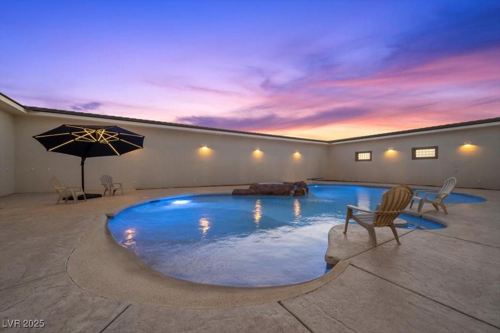 Image 3: Pool at dusk featuring a patio area