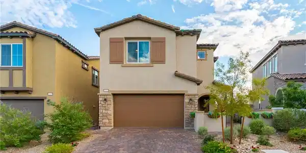 Image 2: Stucco cladding, stone accents, and a paved drivew