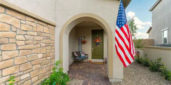 Image 3: An arched entry framed by stone veneer accents lea