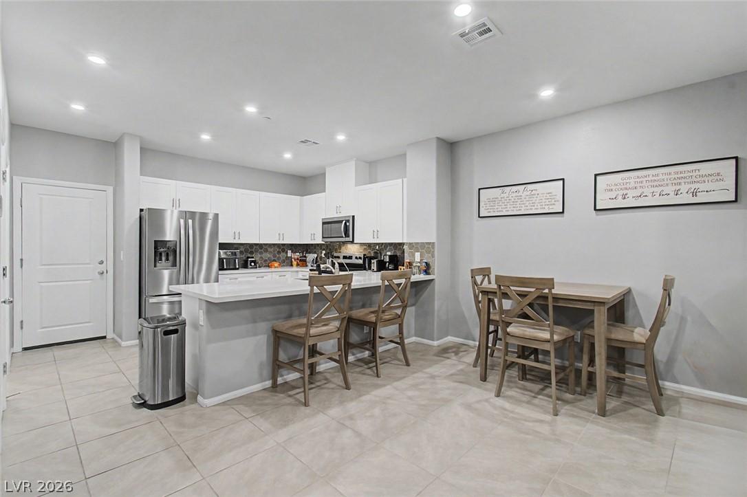 Image 2: A well-lit kitchen and dining area features modern