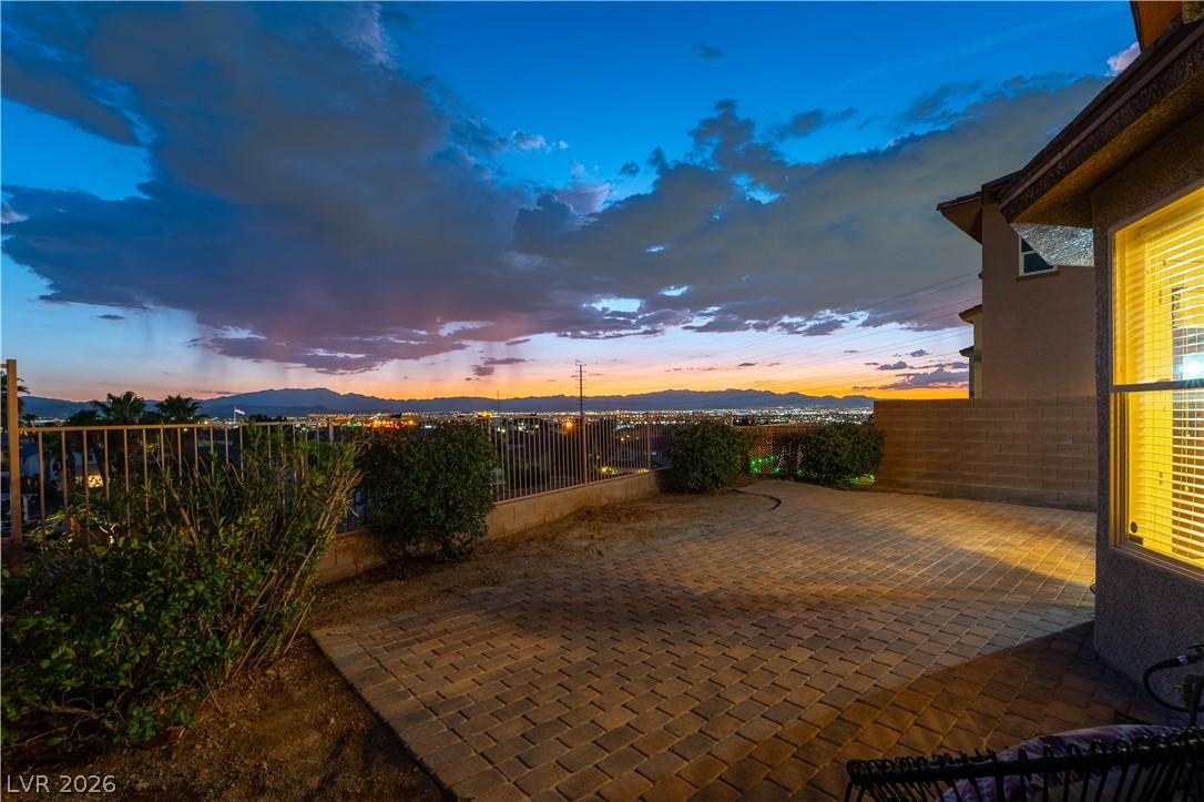 Image 3: City lights twinkle beyond this paver patio, offer