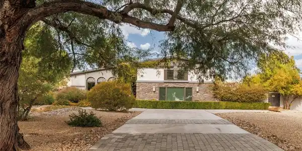 Image 2: Mature trees frame a paved driveway leading to the