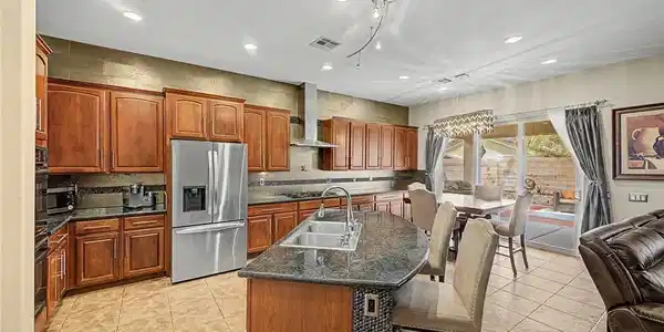 Image 3: A spacious kitchen features warm wood cabinetry, g