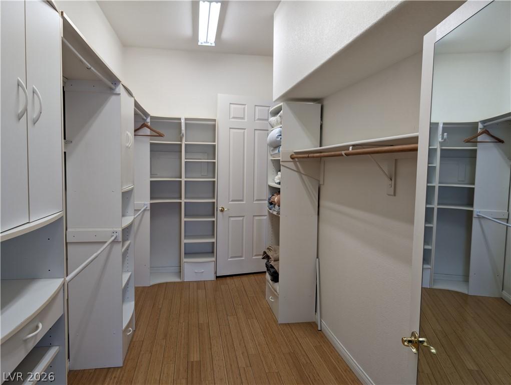 Image 4: Walk in closet with light wood-style floors