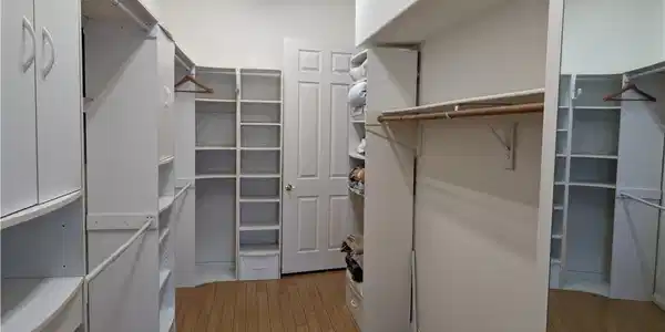 Image 4: Walk in closet with light wood-style floors