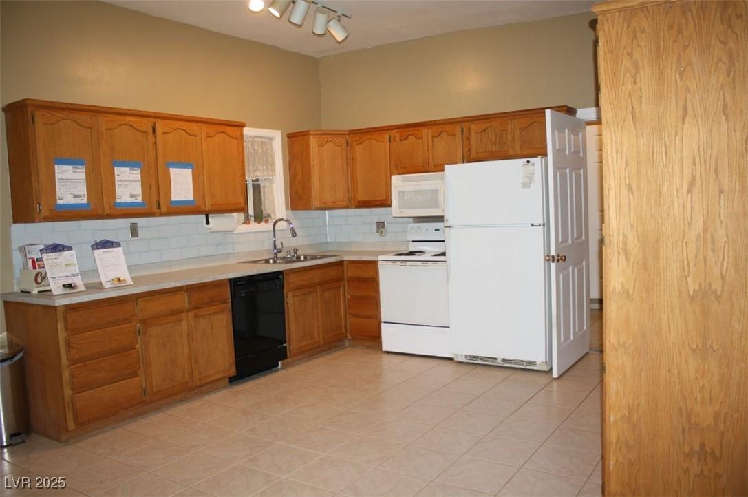 Image 3: Kitchen with white appliances, brown cabinets, bac