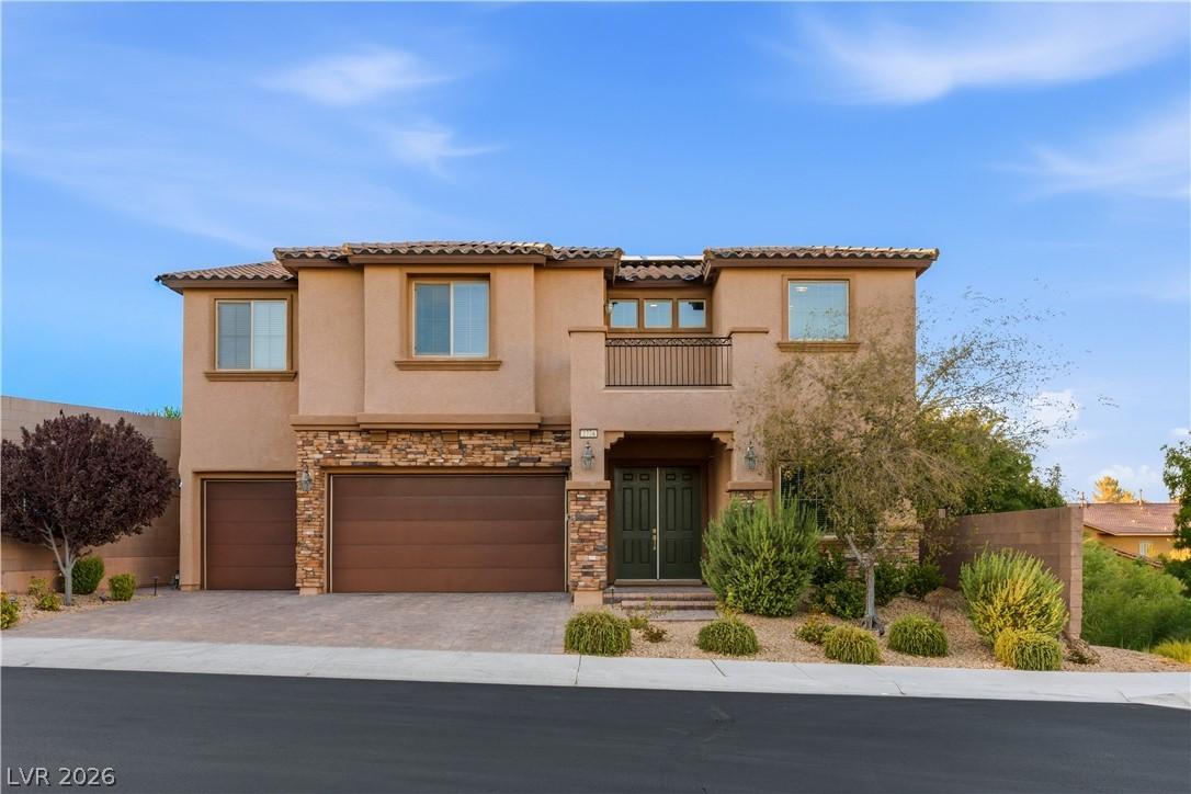 Image 1: A striking stucco and stone exterior home features