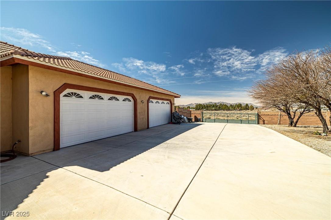 Image 2: View of side of home with a garage, driveway, a ti