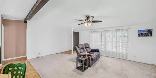Image 4: A spacious living area features a beamed ceiling a