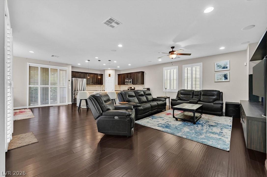 Image 3: An open concept living area boasts dark hardwood f