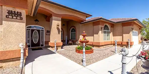 Image 4: A well-maintained stucco home welcomes with an orn