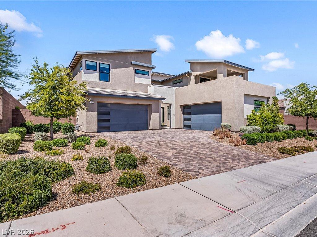 Image 1: A modern facade with dual garage doors and paver d