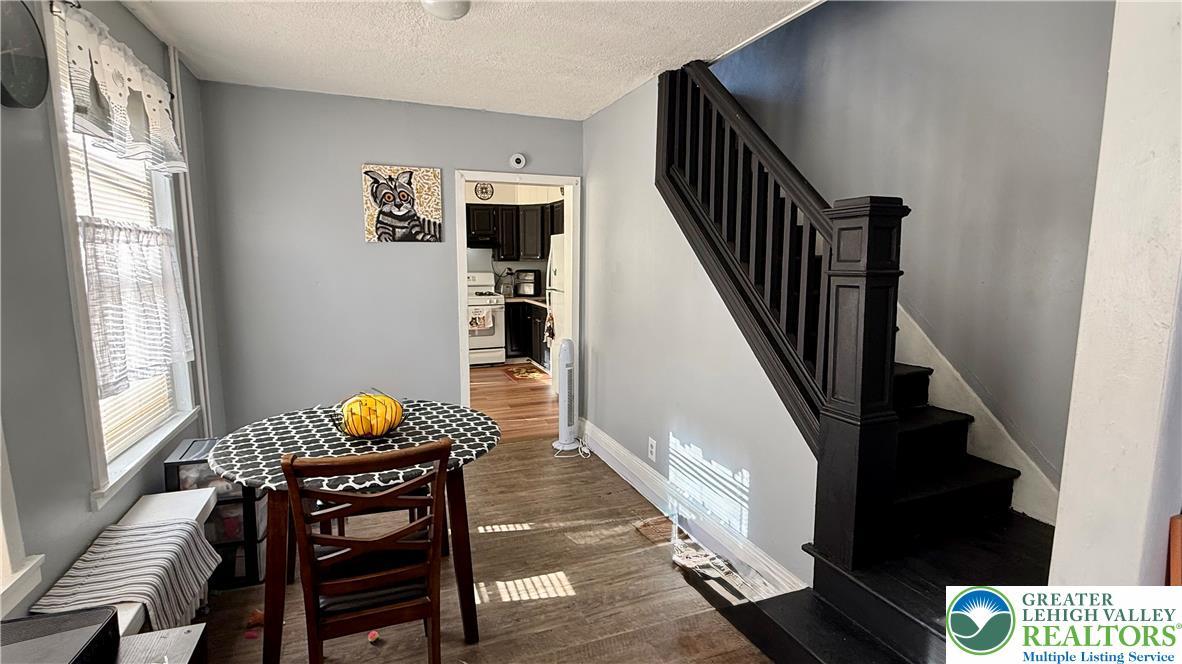 Image 4: Large dining room with a dark wooden staircase pro
