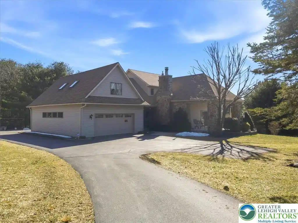 Image 1: A graceful paved driveway leads to a stone and sid