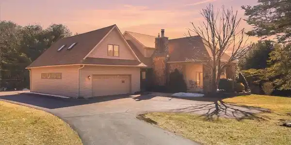 Image 2: A grand, stone-accented home with an attached gara