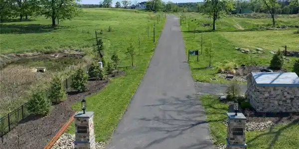 Image 4: A long paved driveway winds through rolling green