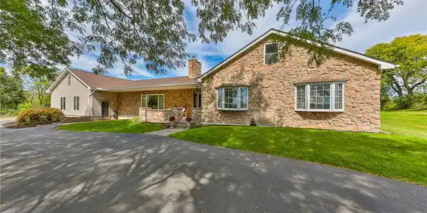 Image 2: Textured stone veneer and a spacious paved drivewa